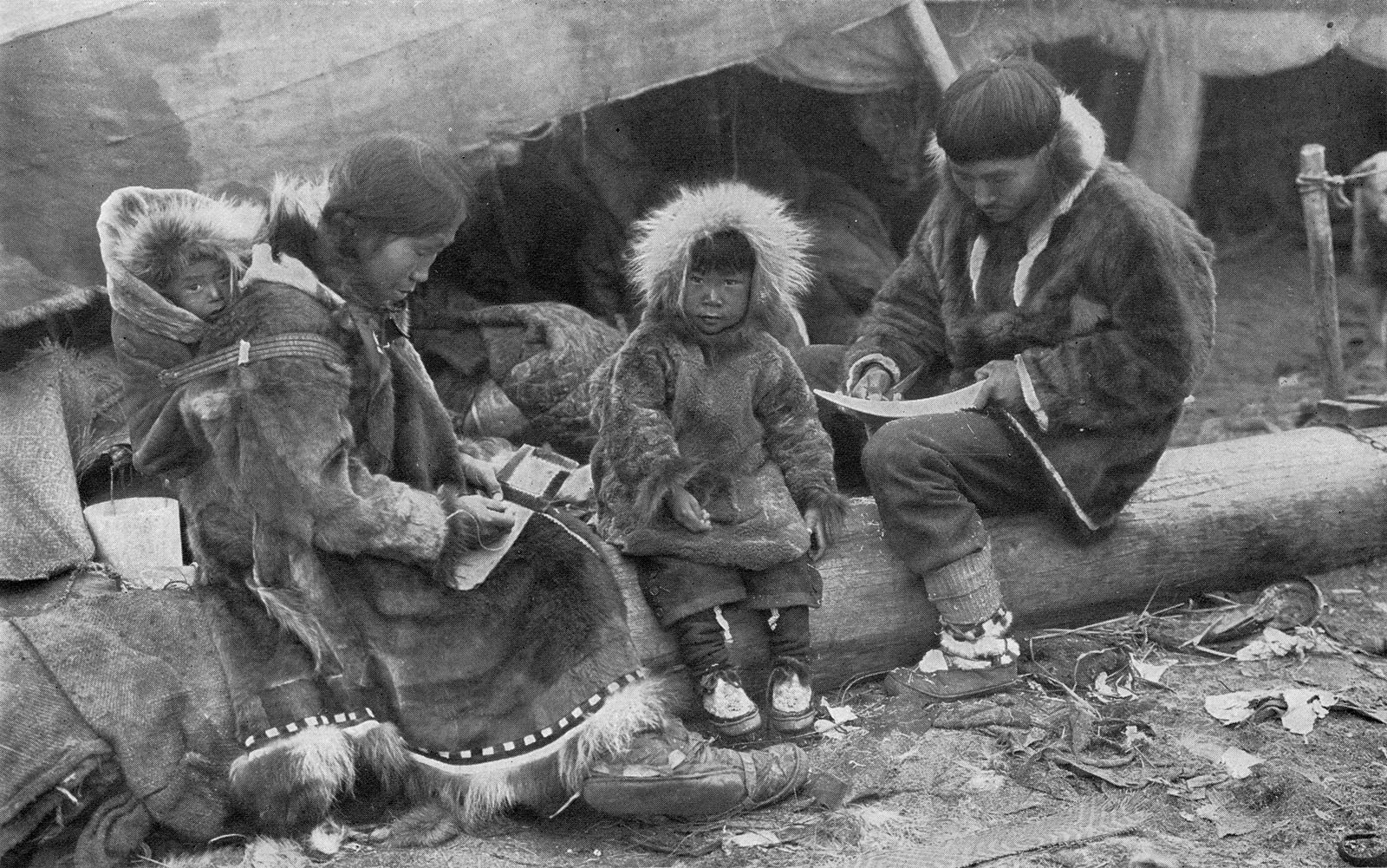 Black and white photograph of traditional inuit sitting on a log